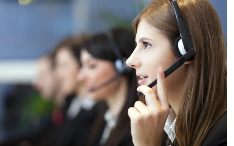 A team member wearing a headset, taking a call at a support desk.